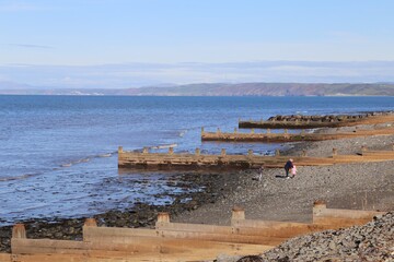Wooden groynes preventing the erosion of the shore on the coast in Aberaeron, Ceredigion, Wales, UK.