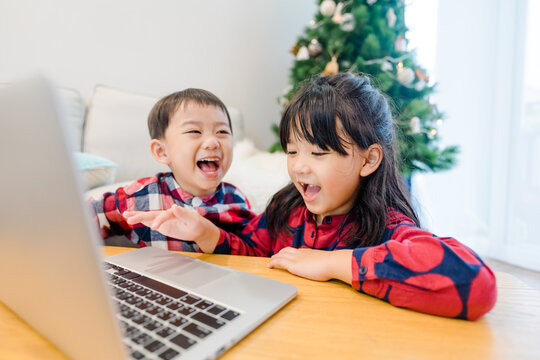 Asian Kids Sibling Sister Brother Video Call In Christmas Holidays Celebrate At Home.Online Video Call Zoom.Kids Watching Video With Laptop.New Normal.Covid-19 Coronavirus.Social Distancing.stay Home.