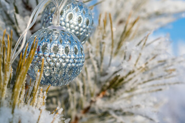 Winter background. Silver balls garland on a branch.