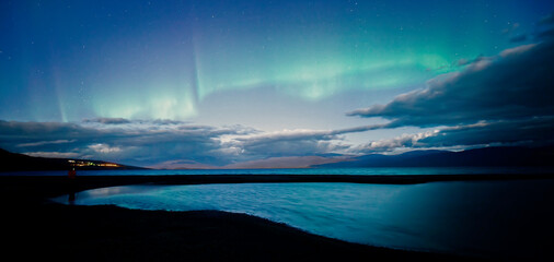 Northern lights dancing over calm  lake in Abisko national park in north of Sweden.