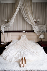 bride's wedding shoes and wedding dress on the bed