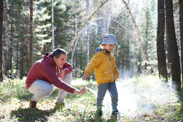 Father spraying insect repellents on his son before a walk in the forest 