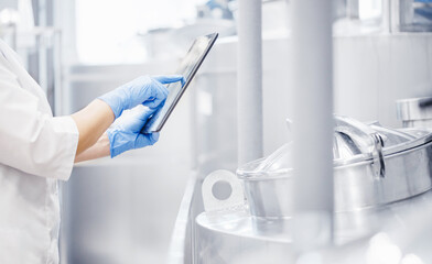 Operator uses tablet computer to check quality and temperature of yeast fermentation in tanker hops and malt, beer production - obrazy, fototapety, plakaty