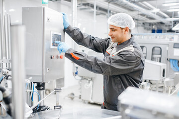 Factory engineer man operating machine control panel in dairy milk production plant