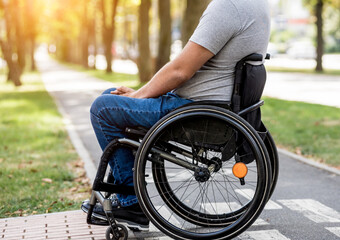 Obraz premium Handicapped man in wheelchair preparing to cross the road on pedestrian crossing
