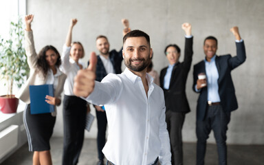 Fototapeta na wymiar Arab Businessman Gesturing Thumbs Up Standing With Employees In Office