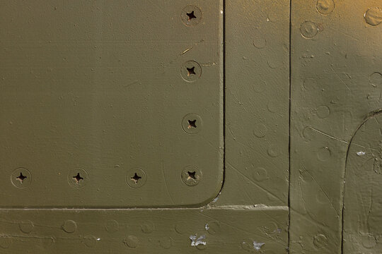 Details of the fuselage of an old aircraft. Camouflage surface with paint and rivets on a military aircraft.