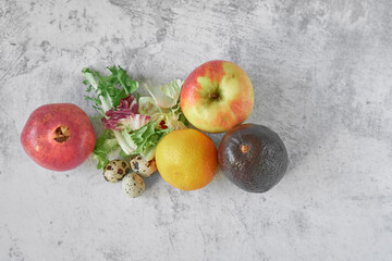 Top view. Pomegranate, quail eggs, lettuce leaves, mandarin, apple, avocado on a gray concrete background. Healthy food for getting vitamins to strengthen immunity. Healthy lifestyle, cooking concept.