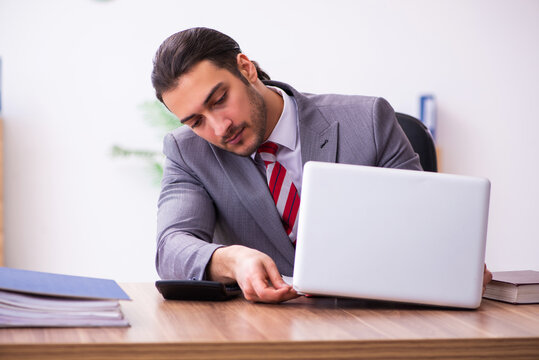 Young male employee inserting flash drive into laptop