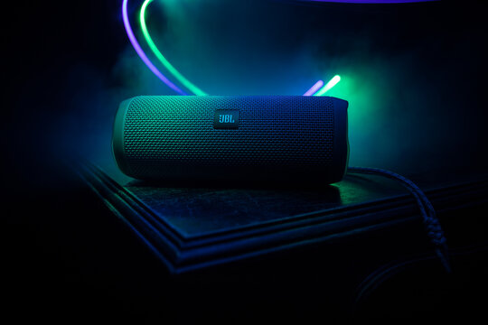 BAKU. AZERBAİJAN &ndash; 28.07.2020: JBL Flip 4 Bluetooth Speaker close up shot on wooden table with colorful lights and fog on background.