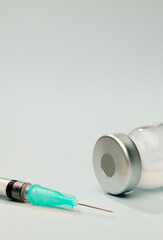 blue cannula syringe with vaccine in vial, green background