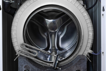 Washing machine repair. Disassembled washing machine with drum and  descaling turbular electric heating element. Close up