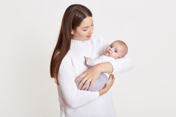 Closeup portrait of beautiful European woman holding on hands her little daughter on white background. Family, love, lifestyle, motherhood and tender moments.