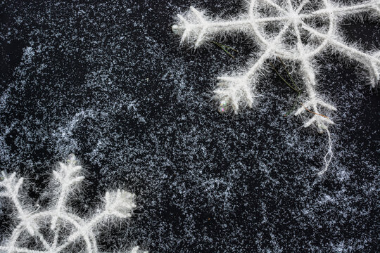 Winter Christmas frame and decorations. Large Artificial snowflakes on black background covered with snow with space for text. Copy space. Christmas template, mockup. Flat lay. Top view - Powered by Adobe