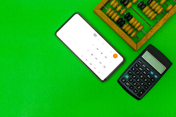 Technological progress concept. Calculation, counting technologies development. Old wooden abacuses, calculator and smartphone with calculator on green background. Top view. Blank space