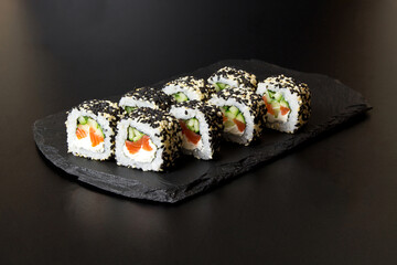 Sushi rolls with sesame seeds on a stone Board for sushi