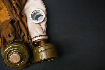 Vignetted image of dirty gas mask with filter and army pouch, belt kit  on black grunge background...