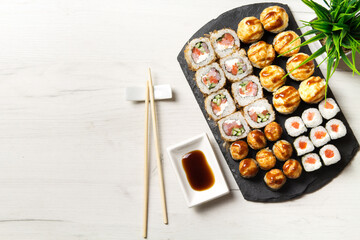 Sushi rolls set on a stone Board for sushi on a light backgroundSushi rolls set on a stone Board for sushi on a light background