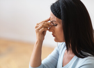 Fatigued upset middle-aged older woman massaging nose bridge