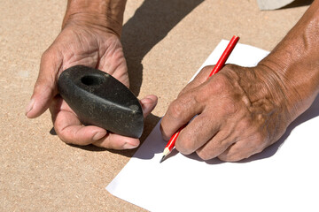 An old stone Hammer an elder man holds in his hands. Archaeology. Study of ancient objects