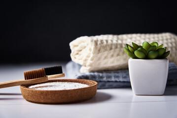Bamboo toothbrushes, baking soda and bathroom towels on dark background
