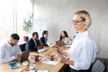 Serious Businesswoman Holding Digital Tablet Browsing Internet Standing In Office