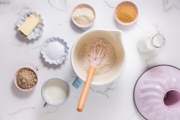 Baking ingredients and kitchen utensils on white wooden background