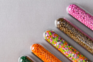 Plastic pellets .Polymeric dye in test tubes on gray background.