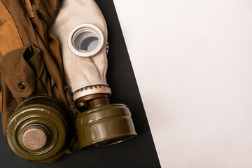 Vignetted image of dirty gas mask with filter and army pouch, belt kit  on black and white...