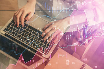 Double exposure of woman hands typing on computer and forex chart hologram drawing. Stock market...