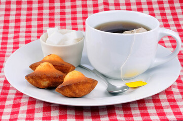 Tasse de thé avec des madeleines et du sucre en morceaux en gros plan