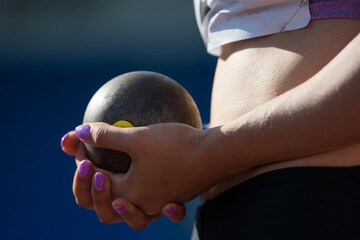 The athlete holds the projectile (shot) in the shot put. Close-up