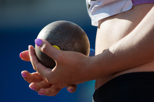 The athlete holds the projectile (shot) in the shot put. Close-up