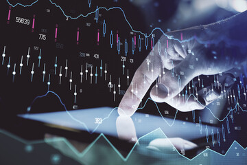 Double exposure of man's hands holding and using a digital device and forex graph drawing. Financial market concept.