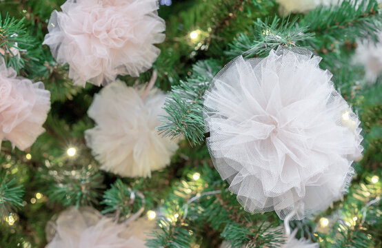 Christmas tree decorated with garland and white fatin bows.