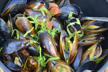 Ravda, Bulgaria. May, 24,2014. Sea mussels in wine sauce with a pinch of green onion in black pan. Traditional food.