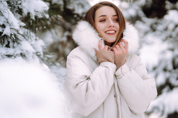 Young beautiful woman  posing in a snowy park. Cold weather. Winter fashion, holidays, rest, travel concept.