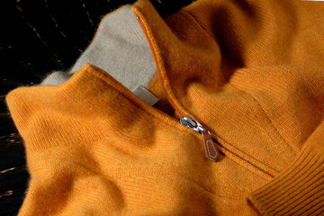 Knitted cashmere sweater in bright orange color. Zipper, macro, close-up.