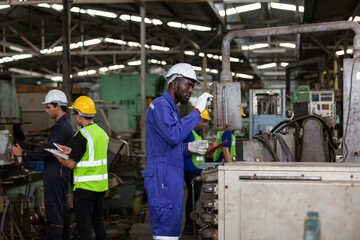 Multi-ethnic factory worker working together in the industrial factory while wearing safety uniform, gloves and hard hat
