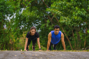 asian athletic couple having push up exercise together outdoors in park