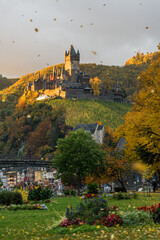 View of Reichsburg with blowing autumn leaves in the morning, Cochem, Rhineland-Palatinate, Germany