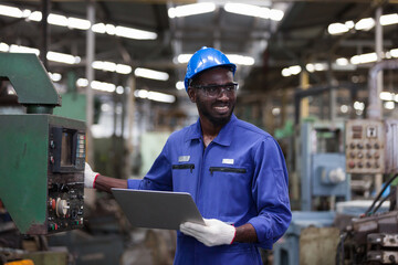 Black male factory mechanic. Smiling black male engineer working with computer laptop for checking...