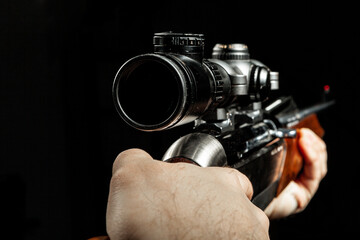 Male hands holding hunting rifle on black background