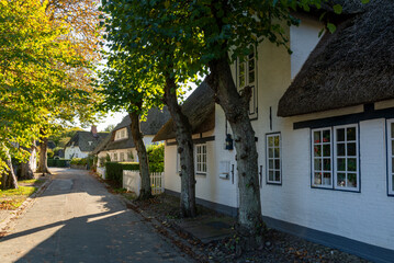 Fototapeta na wymiar Nieblum, Germany - October 16, 2020: Thatched white houses at a street in Föhr