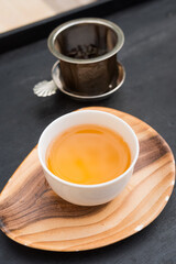 White porcelain tea cup. Fresh natural "Beauté académique" tea, a rolled oolong from Taiwan. Beautiful orange color. Vertical shot.