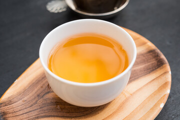 White porcelain tea cup. 
Fresh natural "Beauté académique" tea, a rolled oolong. Beautiful orange color.