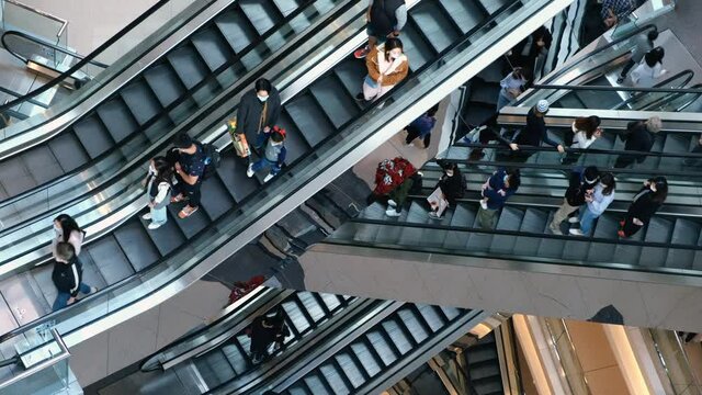 Time lapse of crowd of people in shopping mall. Escalators in modern shopping mall.	