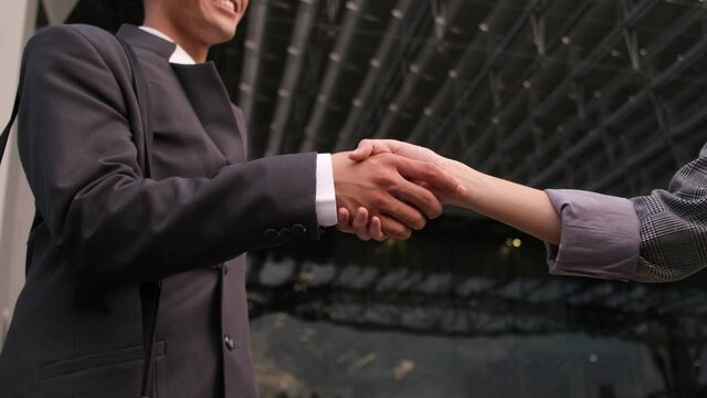 Asian man and woman in a suit, a businessman shaking hands with a woman colleague, a handshake in the office building outdoor.