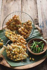 Manadonese Corn Fritters or Bakwan Jagung Manado, served on banana leaves with green chili peppers.