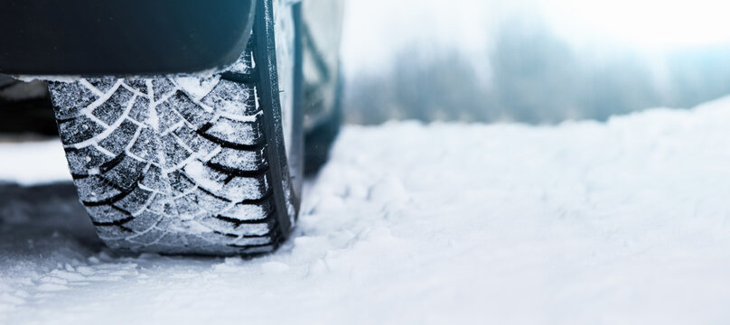 Car is on a snow-covered winter road. Сlose up of winter tire